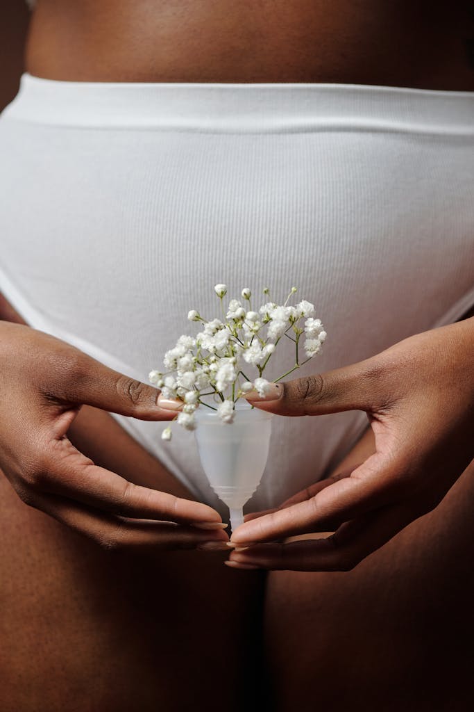 Close-up of hands holding a menstrual cup with flowers, symbolizing feminine health care.