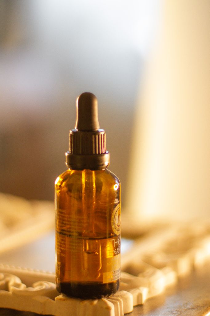 A detailed close-up of a brown glass bottle with a dropper in a warm setting.