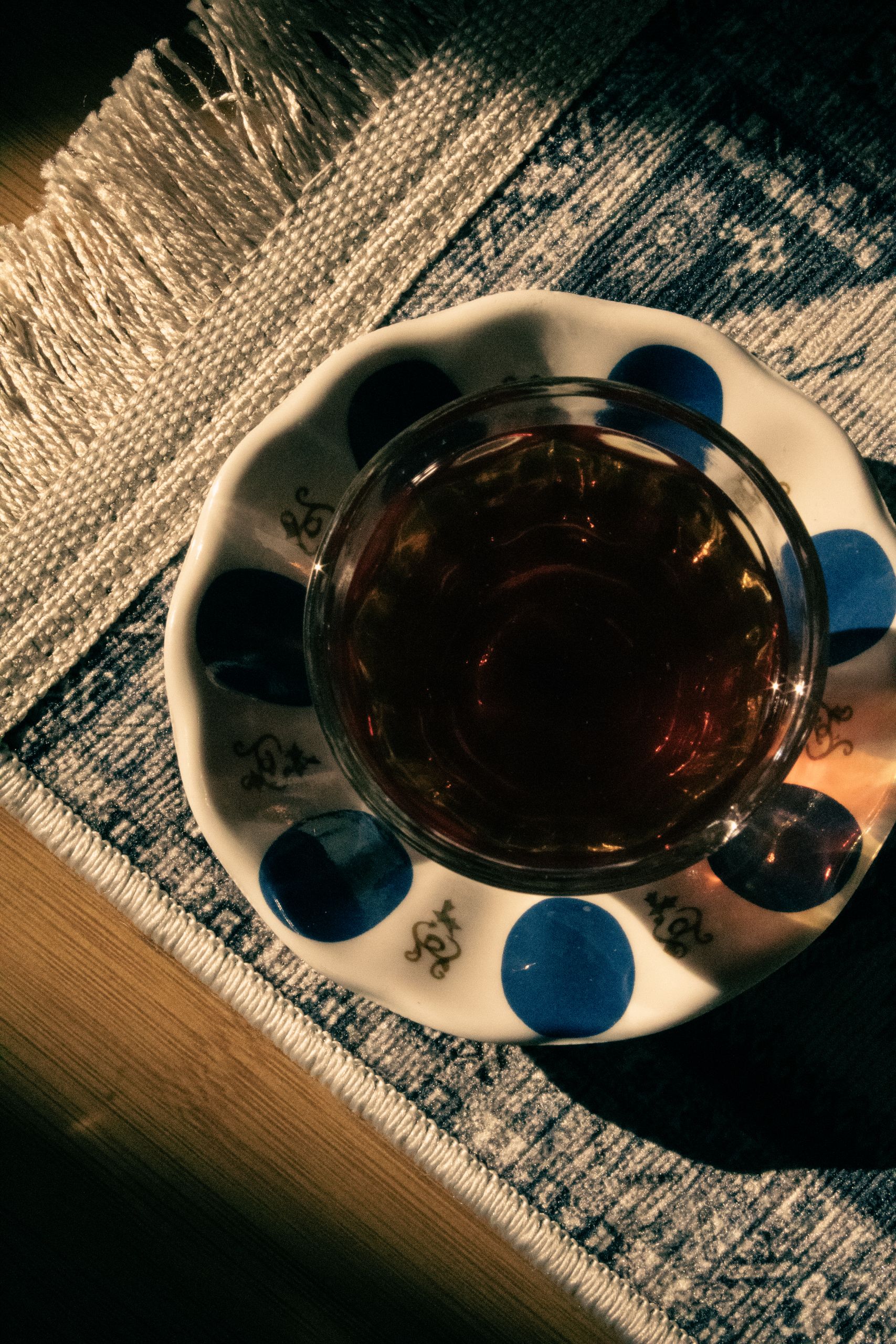 Cozy shot of a tea cup with artistic blue patterns on a textured rug, embodying warmth.